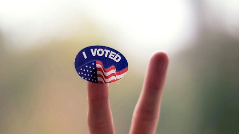 I Voted sticker held up on a fingertip